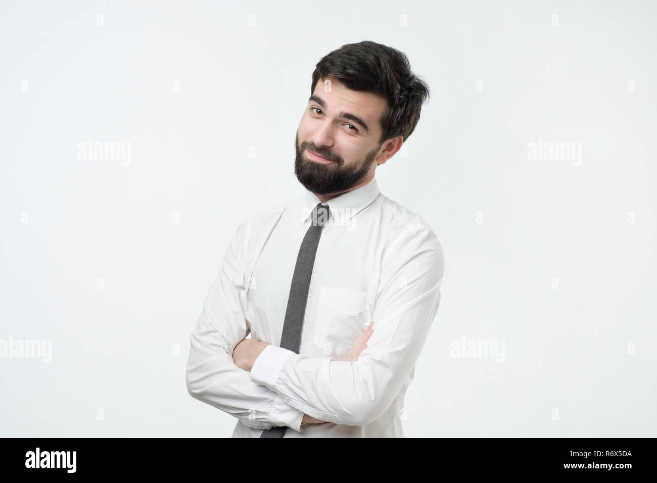 Smiling handsome hispanic man in white shirt crossing hands. Stock Photo