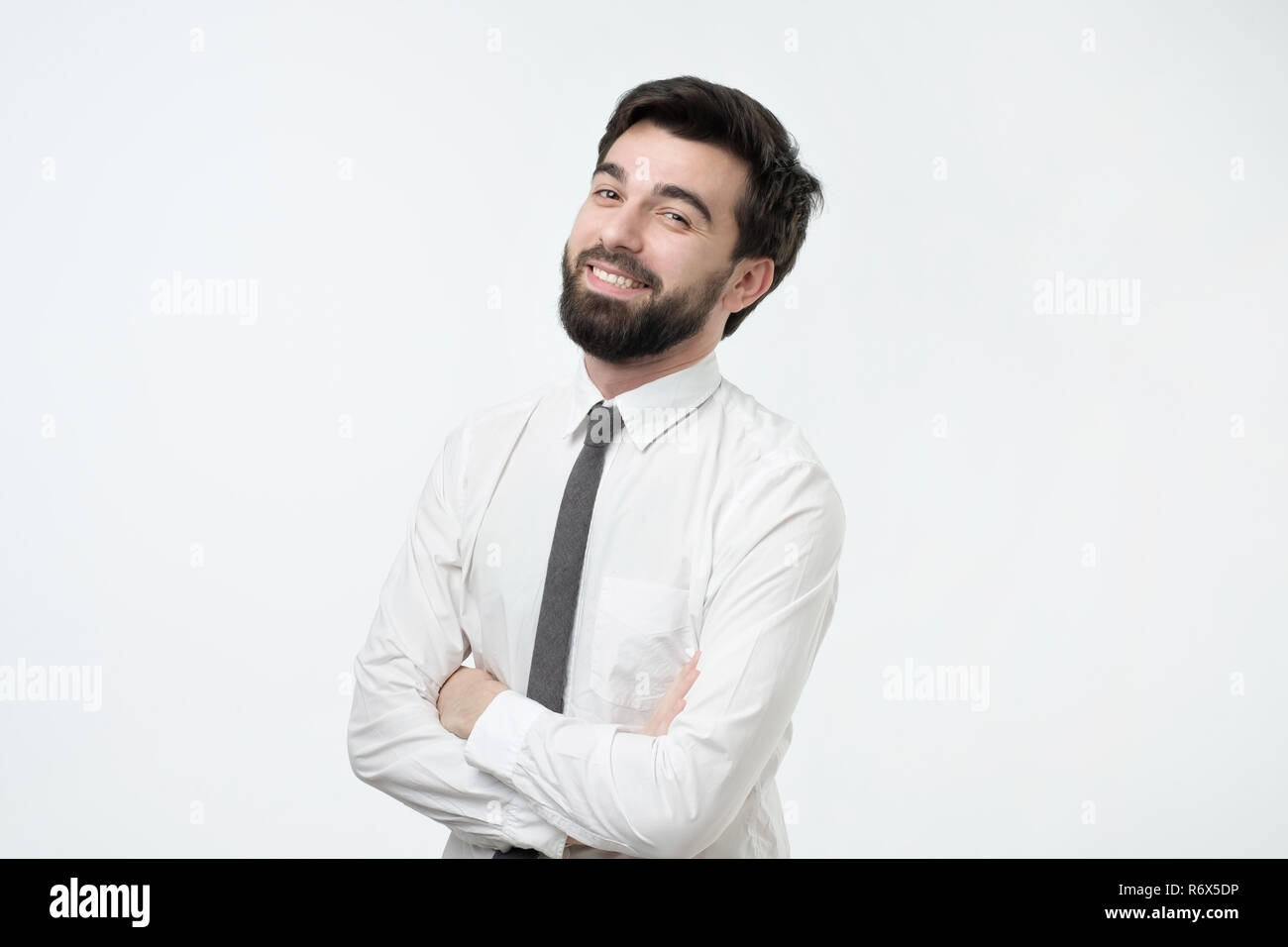 Smiling handsome hispanic man in white shirt crossing hands. Stock Photo