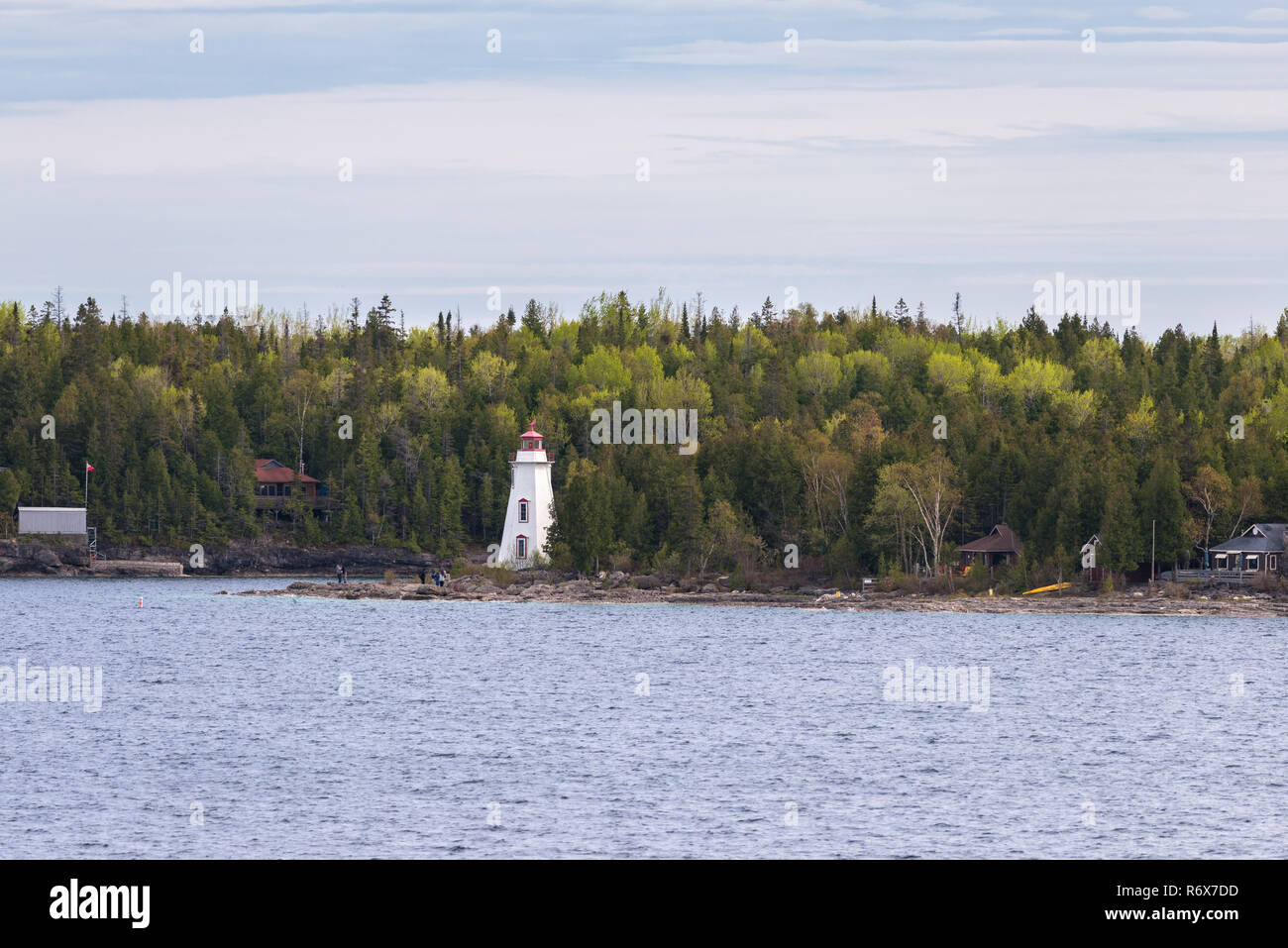 People standing on the rocky coast near Big Tub Lighthouse at the entrance of Big Tub Harbour, Tobermory, Ontario, Canada Stock Photo