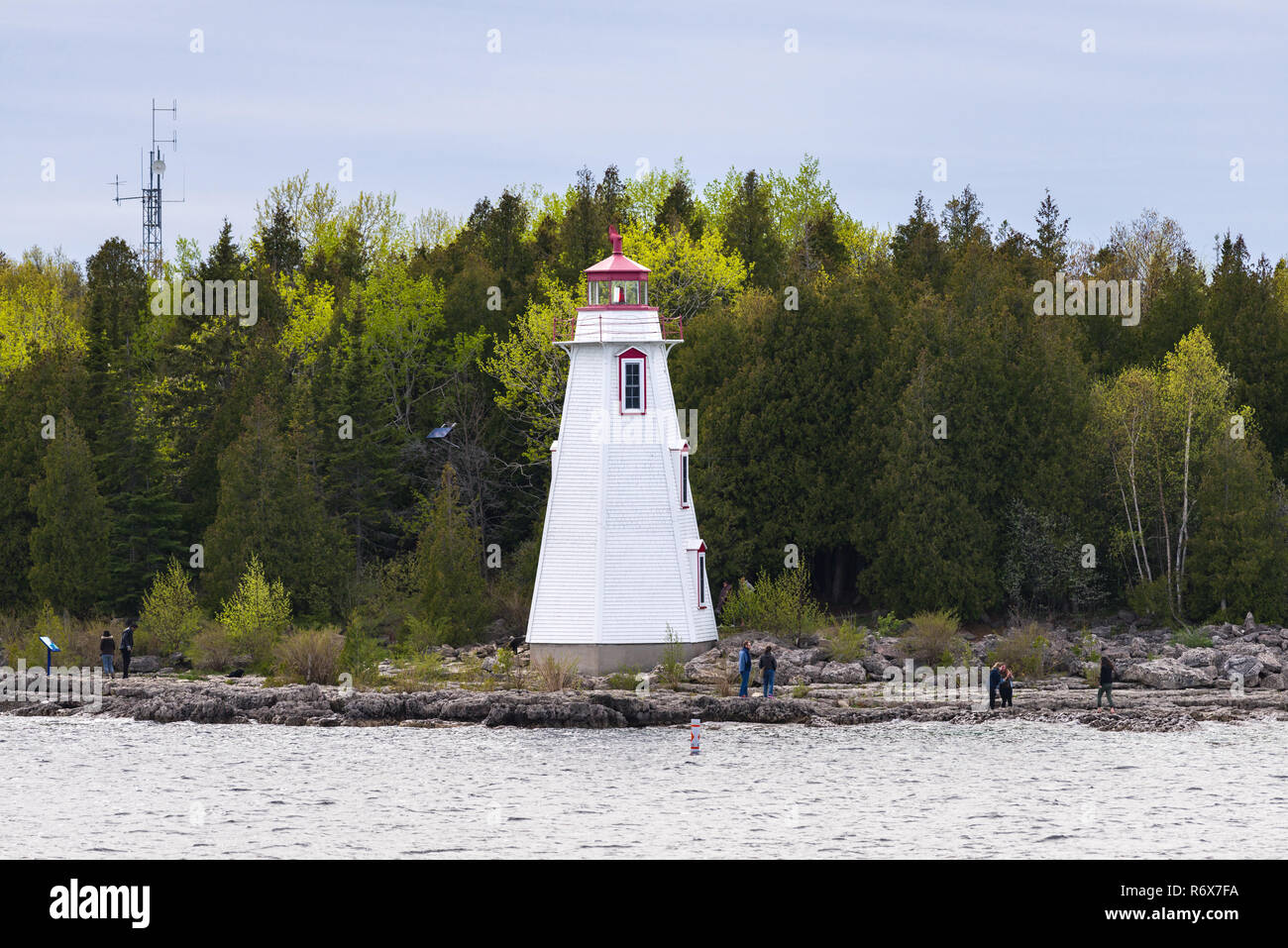 People standing on the rocky coast near Big Tub Lighthouse at the entrance of Big Tub Harbour, Tobermory, Ontario, Canada Stock Photo