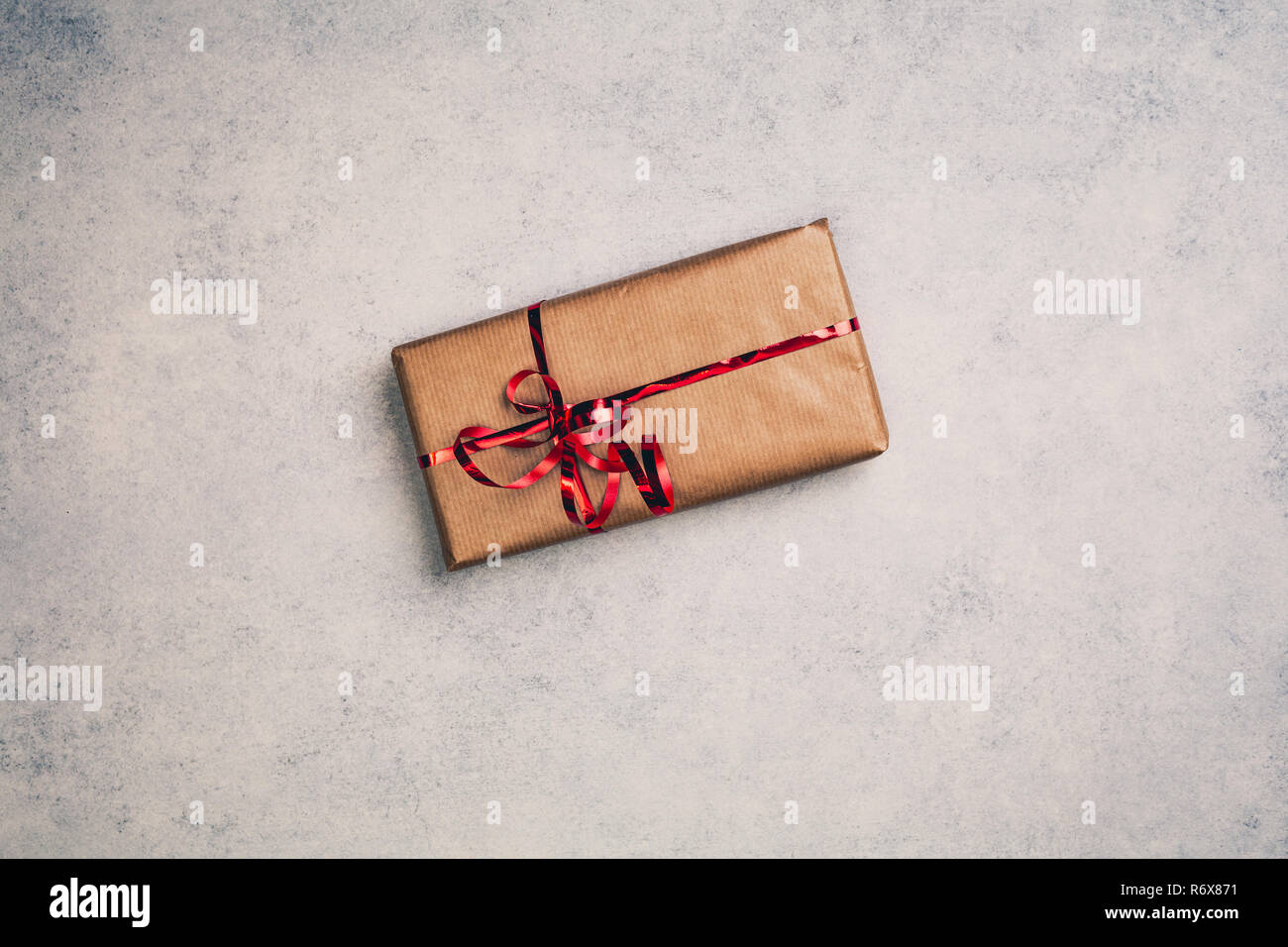 Gift or present in brown paper box with red ribbon, above view. Top centered closeup view with copy space. Stock Photo