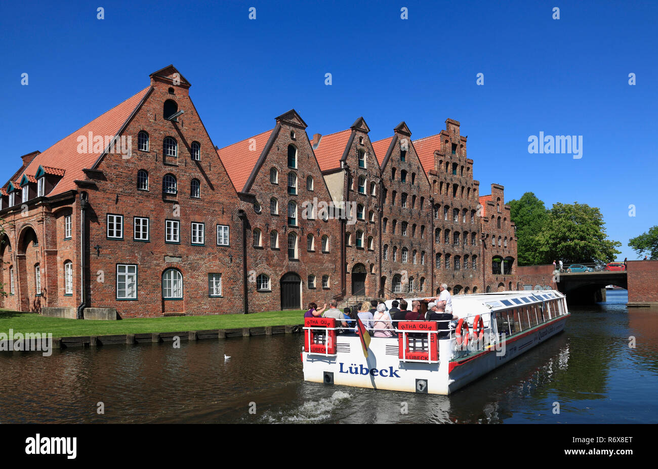 Tourist sightseeing ship in front of historic salt storages at river Trave, Lübeck, Luebeck, Schleswig-Holstein, Germany, Europe Stock Photo