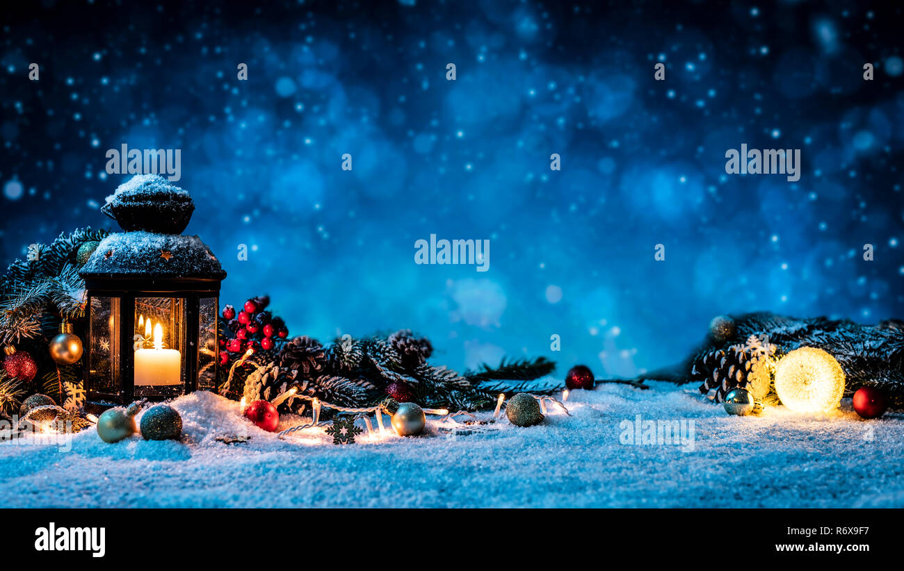 Christmas Card: snowy lantern and candlelight with fir branches and baubles. Stock Photo