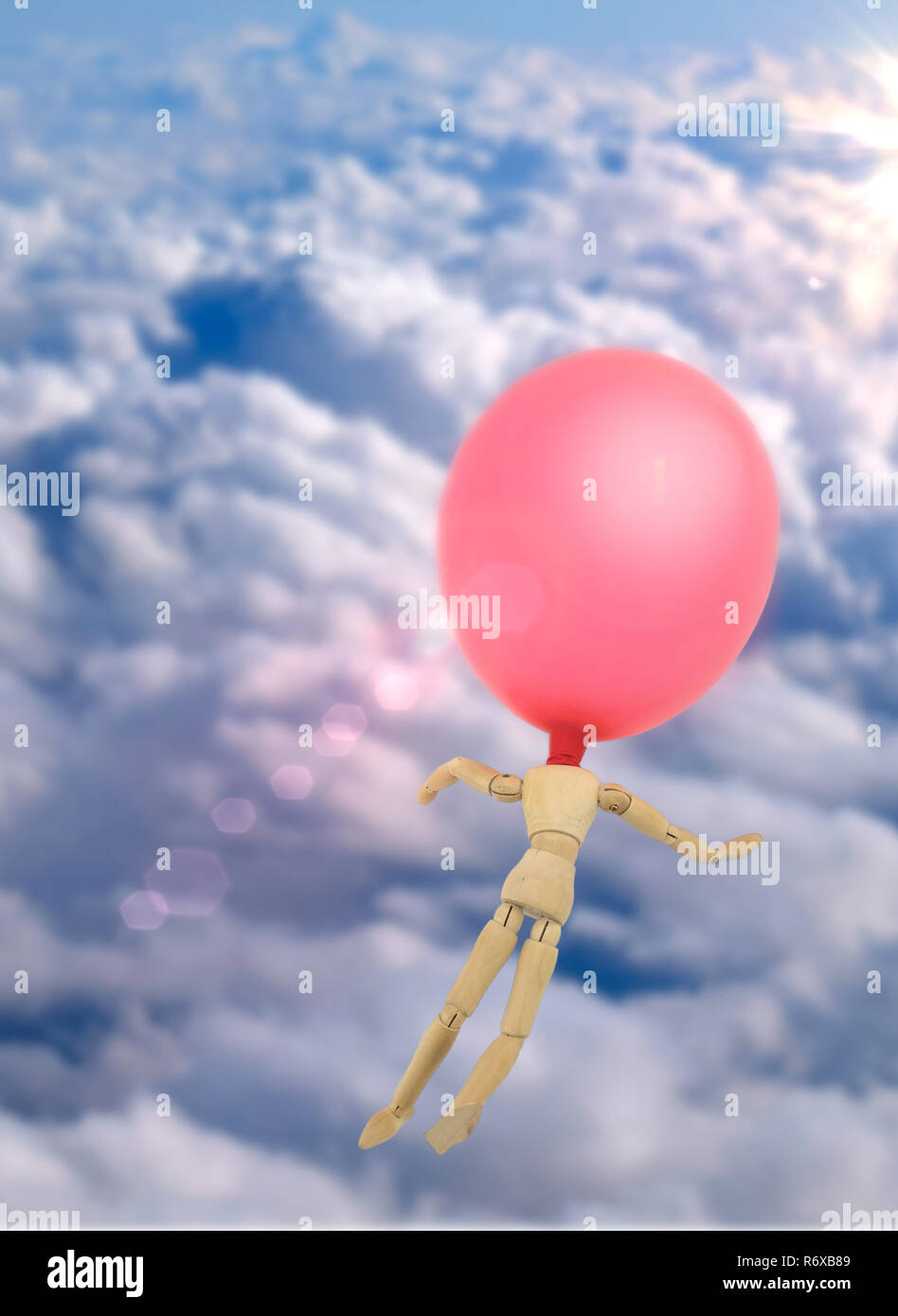 Doll made of wood with balloon in the head flies through the sky, conceptual image Stock Photo