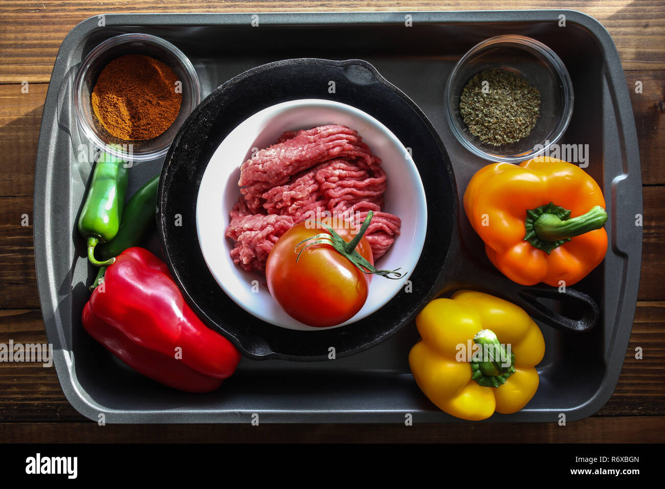 Ground beef, with peppers and other ingredients on baking pan with