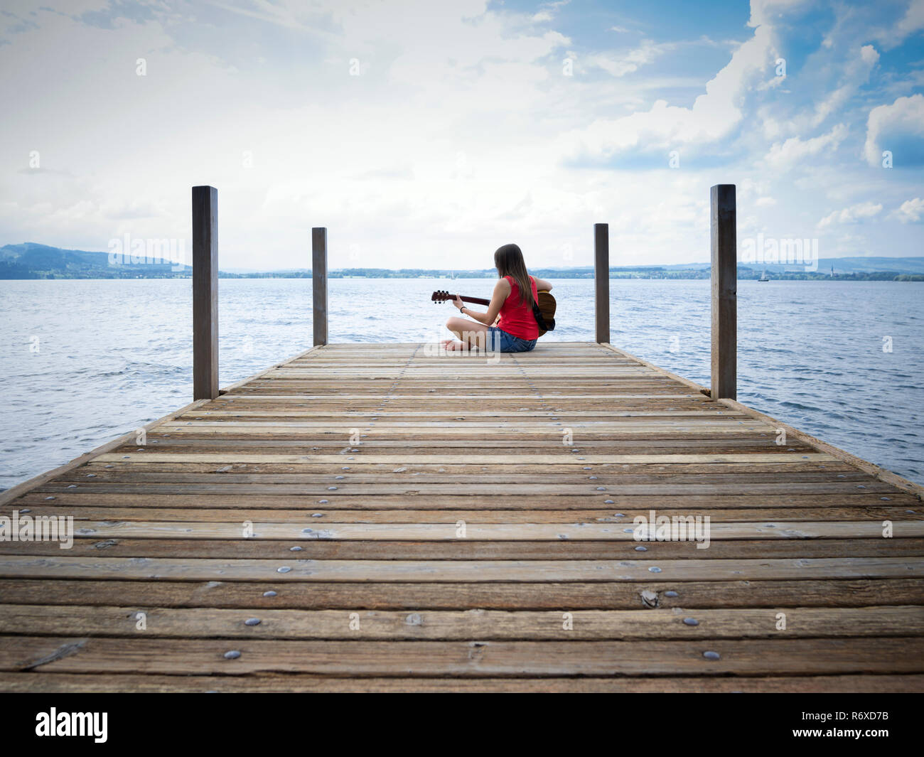 Woman playing guitar by the lake Stock Photo