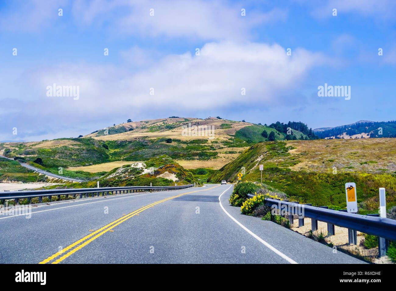 Driving on the scenic Highway 1 (Cabrillo Highway) on the Pacific Ocean coastline close to Davenport, Santa Cruz mountains visible in the background;  Stock Photo