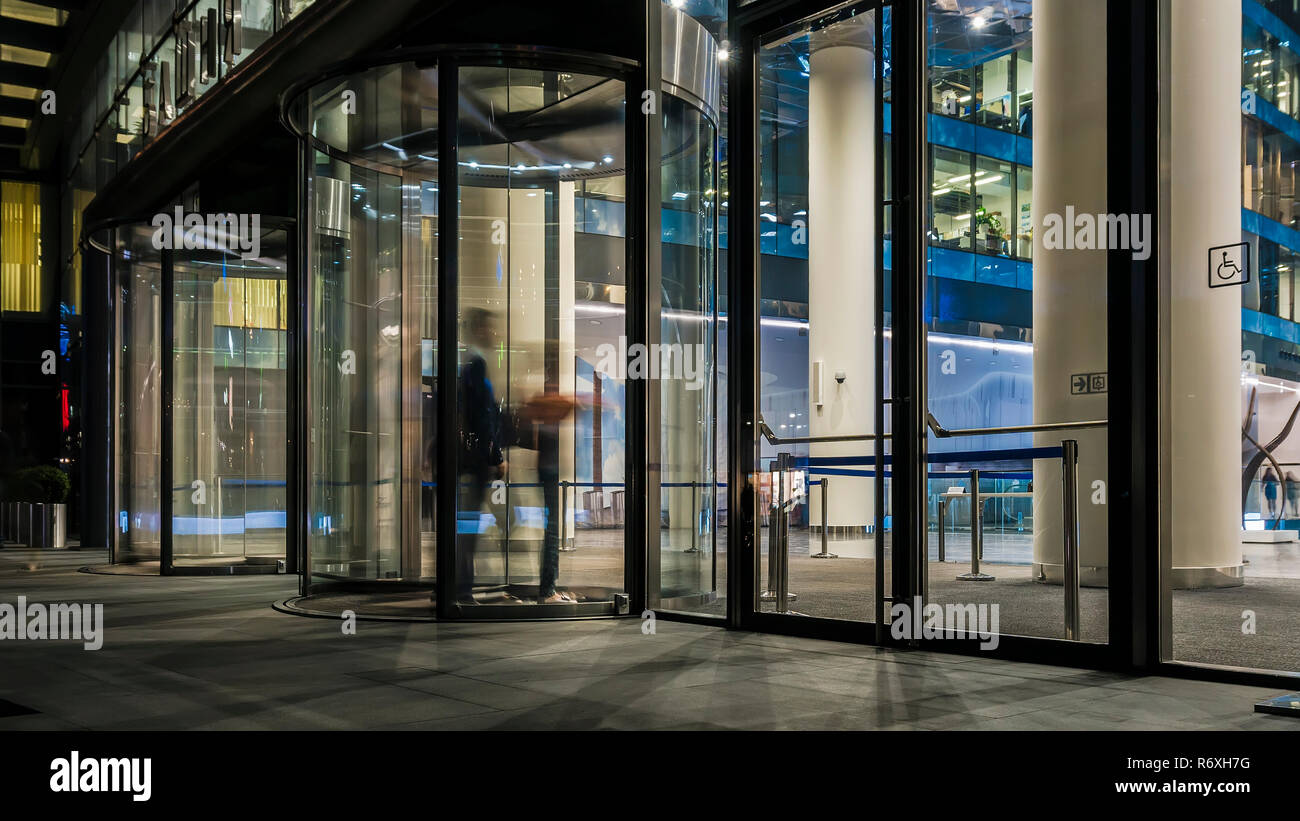 the flow of people passing through the revolving door of the modern office building at the end of the working day Stock Photo