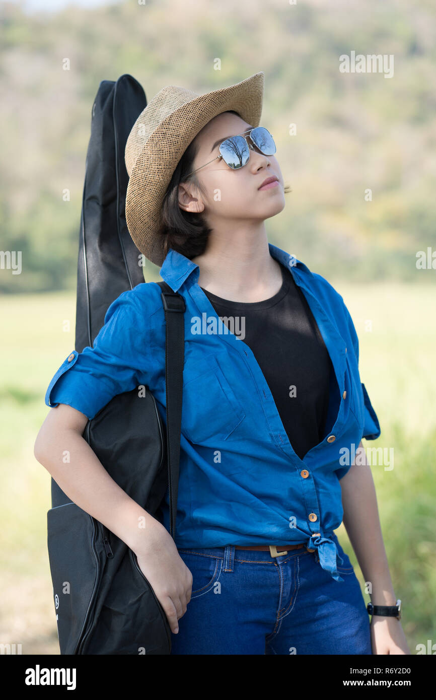 woman wear hat walking and carry her guitar bag Stock Photo Alamy