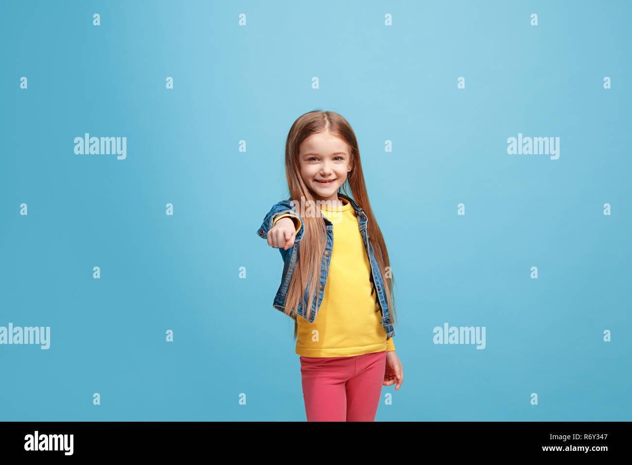 The happy teen girl pointing to you, half length closeup portrait on blue background. Stock Photo