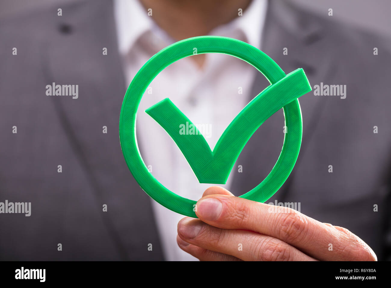 Businessperson Holding Check Mark Icon Stock Photo - Alamy