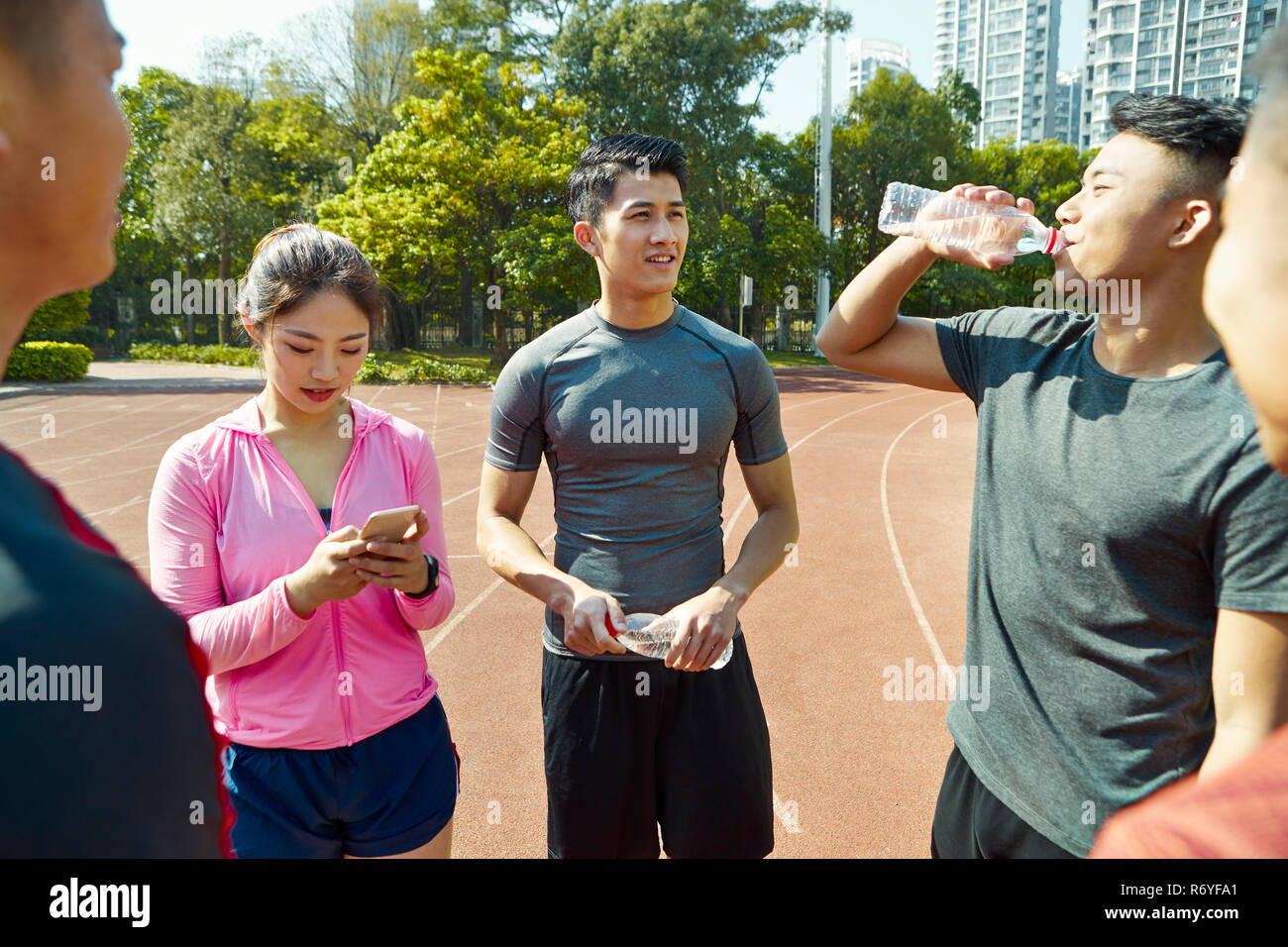 group of young asian athletes talking and relaxing on track after training. Stock Photo