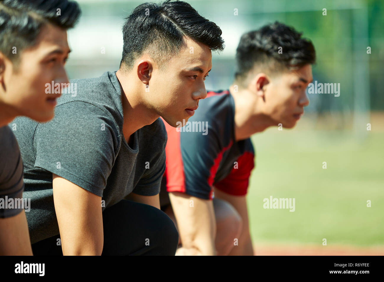 young asian track and field athletes sprinters setting on starting line. Stock Photo