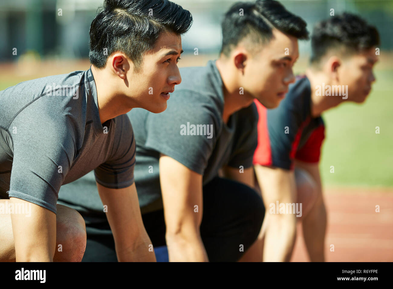 young asian track and field athletes sprinters setting on starting line. Stock Photo