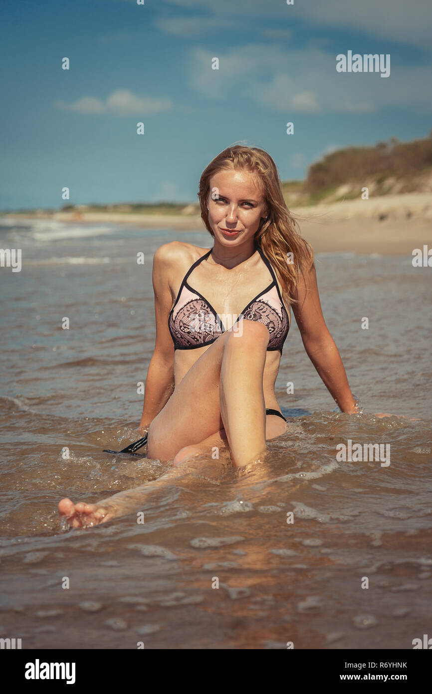 Blond Girl In Swimsuit Sitting At Sea Beach Tanning Stock Photo