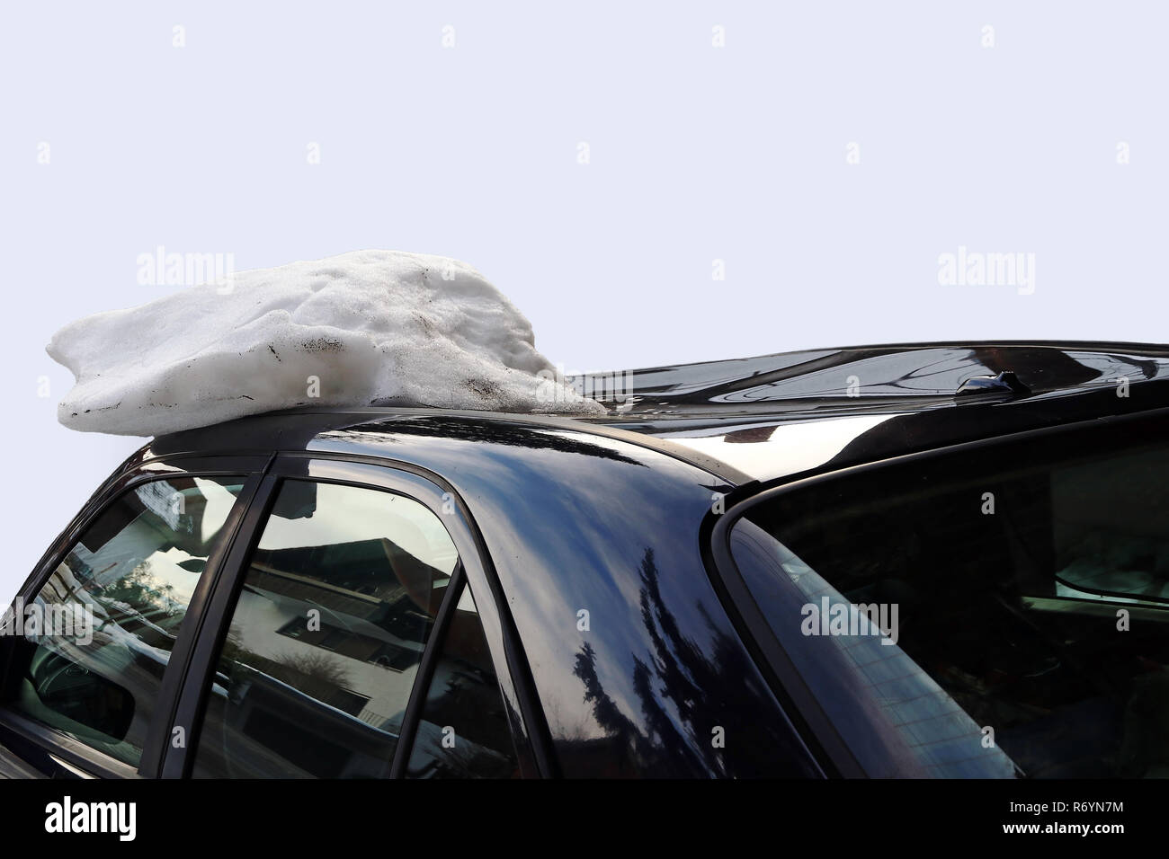 a roof avalanche severely damaged a black car on the roof. damaged by a roof avalanche on a car Stock Photo