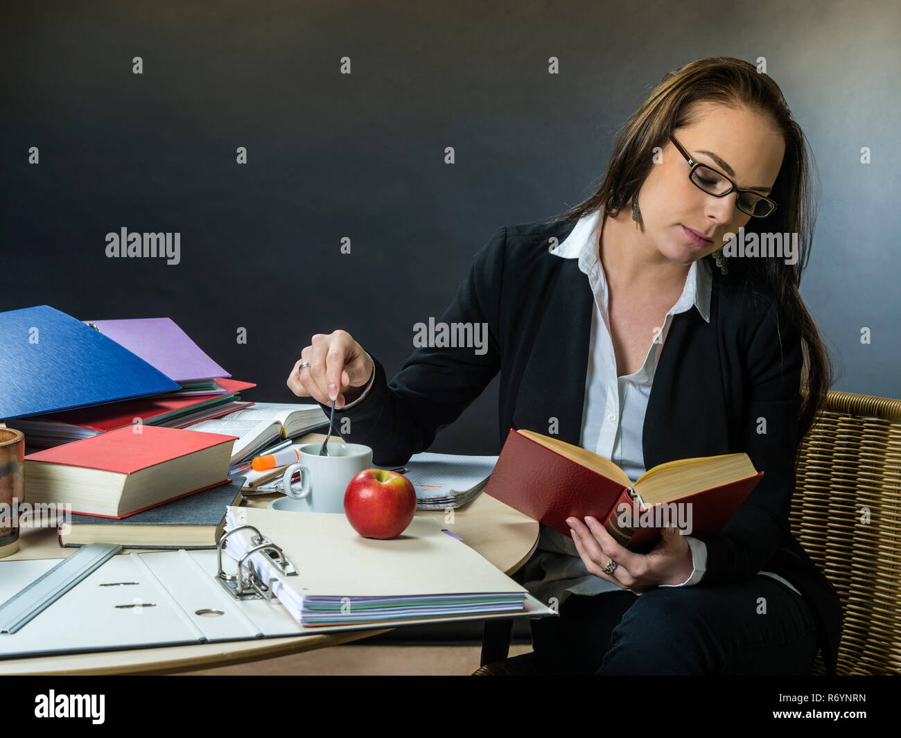 Beautiful teacher sitting at her desk reading Stock Photo - Alamy