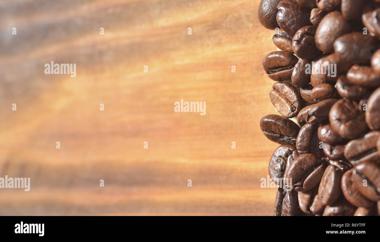 Large roasted coffee beans on a light wooden background Stock Photo - Alamy