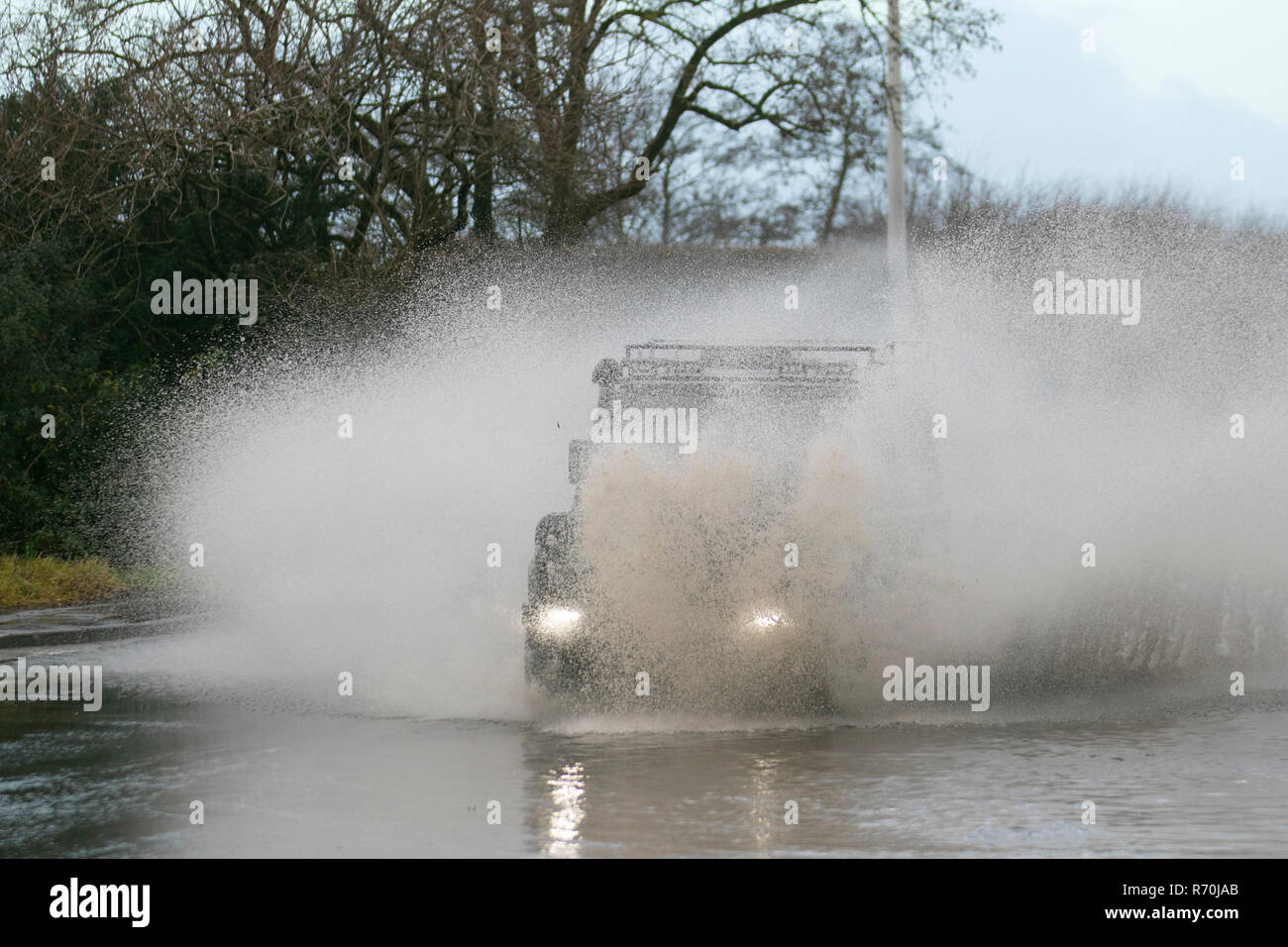 Car driving through deep, fast-flowing water, flooded road in Preston, Lancashire. 7th Dec, 2018. UK Weather: Land Rover, with snorkel exhaust,  driving on flooded roads after heavy overnight rain making for difficult and dangerous driving conditions. Credit: MediaWorldImages/Alamy Live News Stock Photo