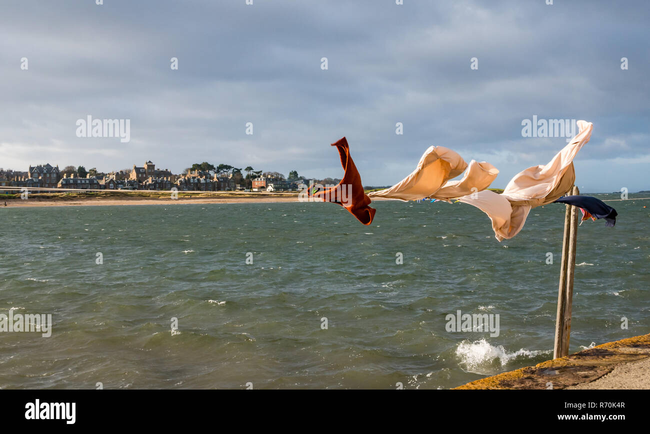 North Berwick, East Lothian, Scotland, United Kingdom. 7th December 2018. UK Weather: A bright sunny but very windy day in the seaside town with washing hanging on a line blowing in the wind in West Bay on the Firth of Forth shore Stock Photo