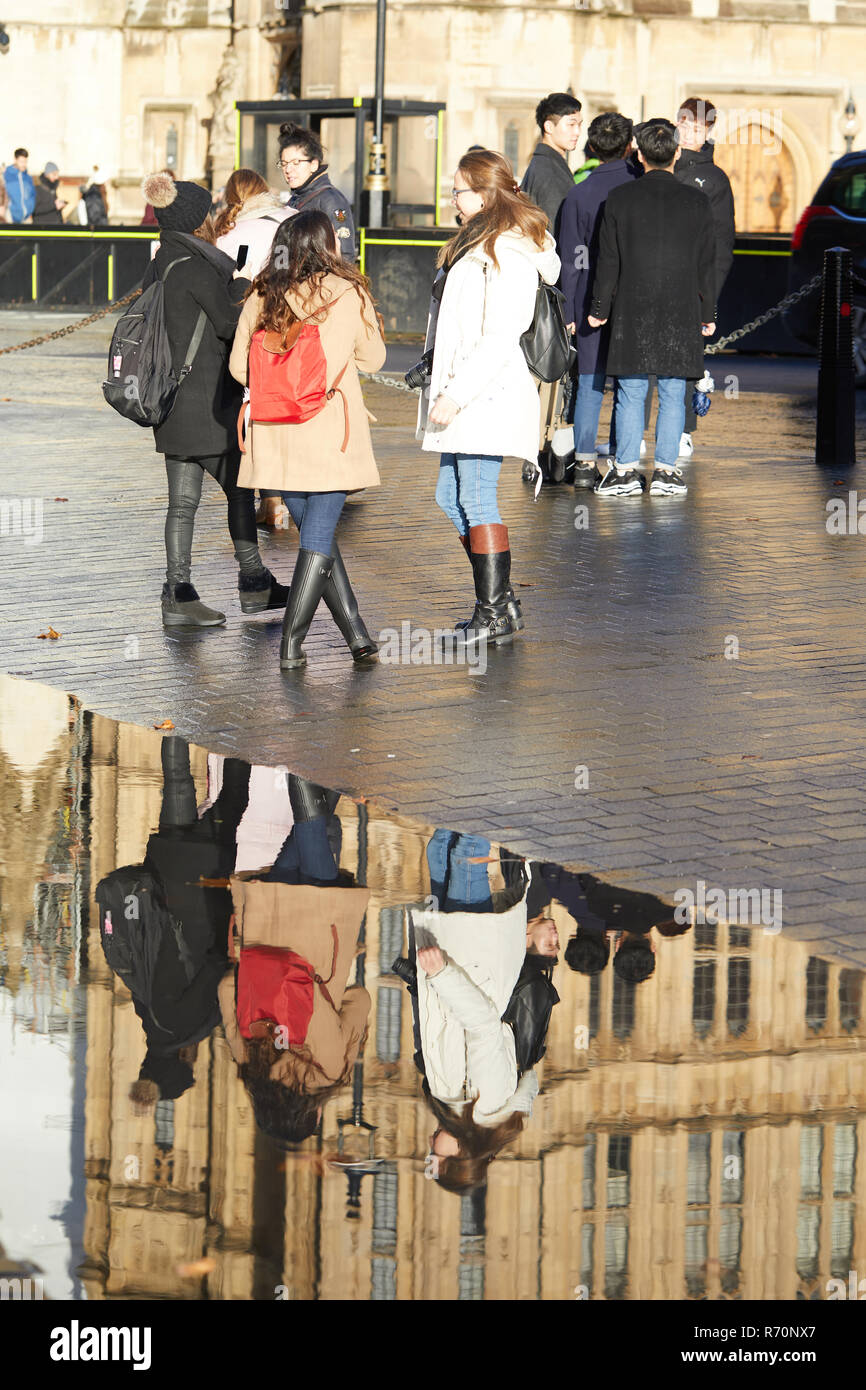 London UK. 7th December 2018. UK Weather. Tourists opposite the Houses of Parliament, seen reflected in a puddle left by heavy morning rains. Credit: Kevin J. Frost/Alamy Live News Stock Photo
