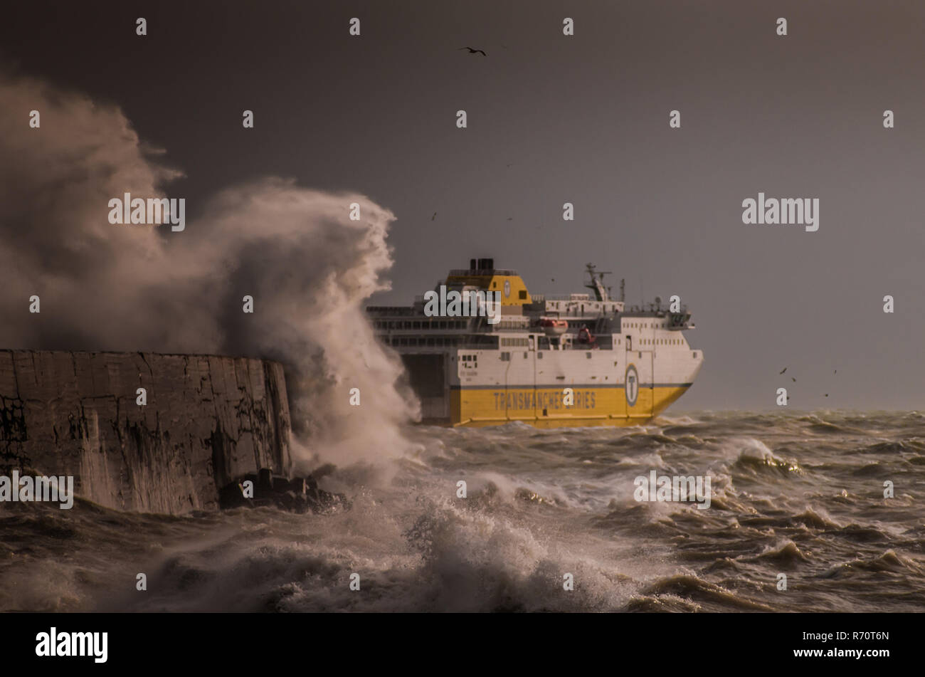 Newhaven, East Sussex, UK. 7 December 2018..Transmanche ferry to Dieppe departs  the Newhaven harbour wall protection into the rough windswept sea. Strong squally  wind from the West with heavy rain but still unseasonably warm at 10 C. Stock Photo
