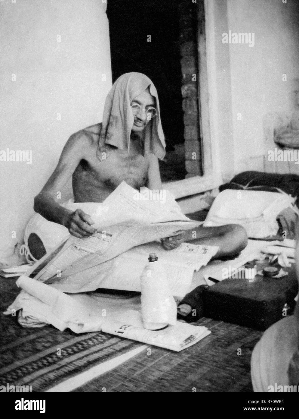 Mahatma Gandhi reading newspaper with towel on head during his tour of Bihar, India, 1934, old vintage 1900s picture Stock Photo