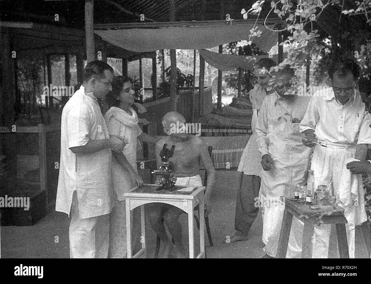 Doctor showing to Mahatma Gandhi microscope hookworm ova, Juhu Beach, Bombay, Mumbai, Maharashtra, India, May 1944, old vintage 1900s picture Stock Photo