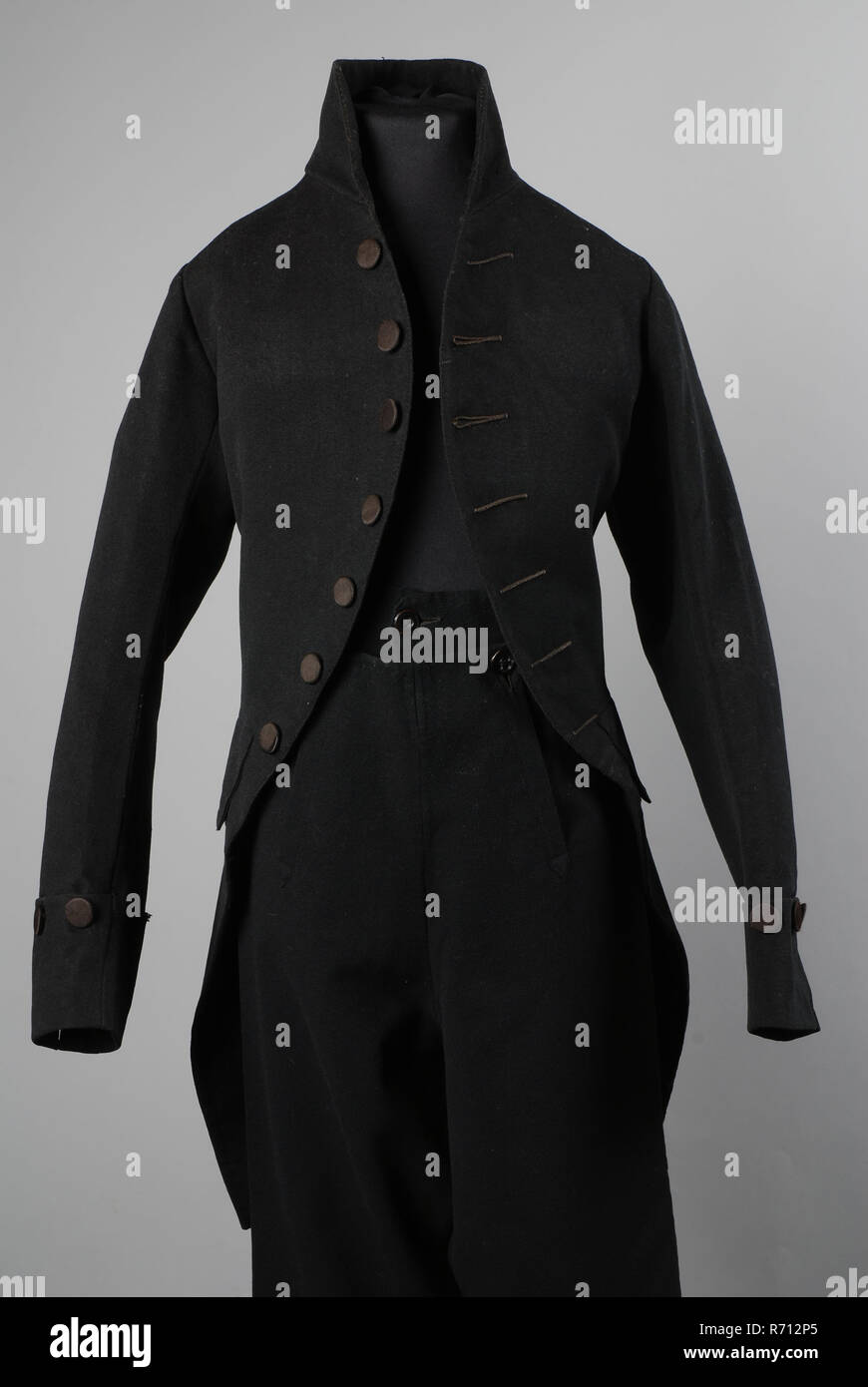 Jacket or habit of black cloth with black silk buttons, part of boys suit, coat suit outerwear boy clothing children's clothing sheep wool wool linen cotton silk mid back, roughed flattened ribbing textile linen Black cloth coat or habit with: round cut away front side panels with seven with black silk covered flat buttons and buttonholes of which two are usable on the chest; standing board; long two-piece sleeves with cuffs with three buttons horizontally; empty pocket flaps on the hips with three knots half underneath; two back panels form diamond; the waist seam runs slightly behind; split  Stock Photo