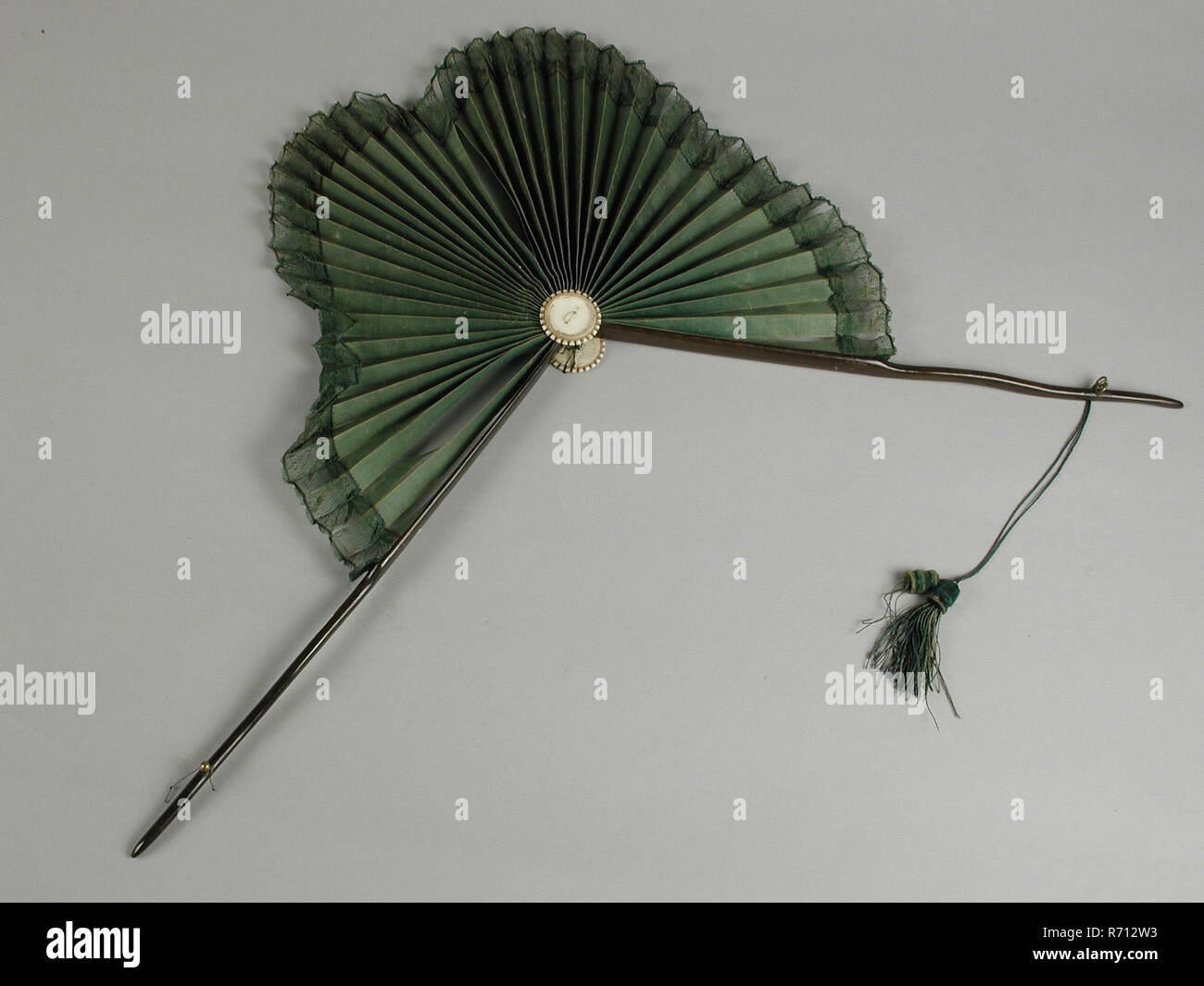 Parasol fan, two thin dark brown wooden legs, leaf shaped fan leaf of
