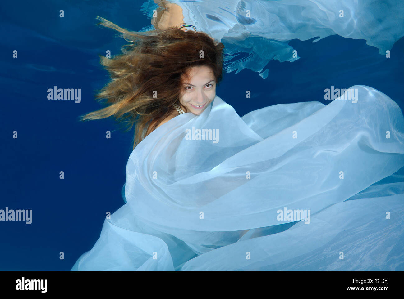 Woman in a long white dress under water, underwater fashion