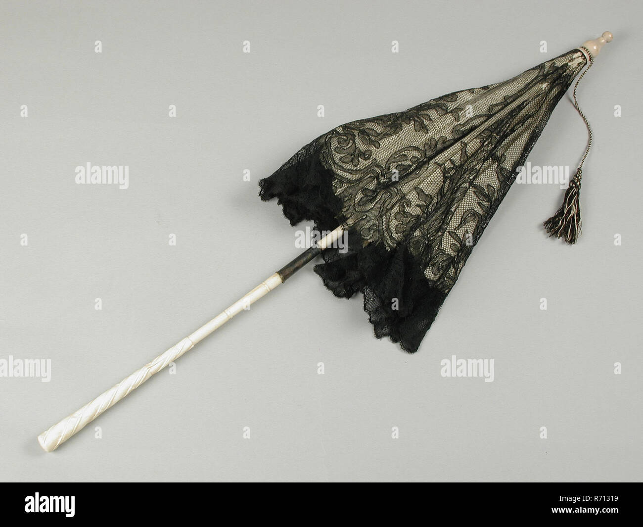 Carriage umbrella with ivory-colored silk trim, black lace, carved handle, carriage parasol clothing accessory women's clothing clothes leg tooth ivory wood metal iron copper silver? textile silk lace cotton linen folded, textile machine side turned Driving Parasol with white silk lining and upholstery with black lace (embroided tulle). The upper half of the handle is made of white lacquered wood, the lower half of worked ivory or bone. Black lacquered metal ribs. Metal silver-plated Wide ring over the hinge White lacquered wooden tip with black-and-white brush attached to it sunlight sun prot Stock Photo