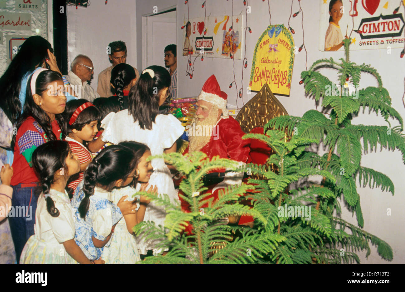 Man wearing costumes and playing character of Santa Clau giving gifts to children on Christmas Occasion Stock Photo