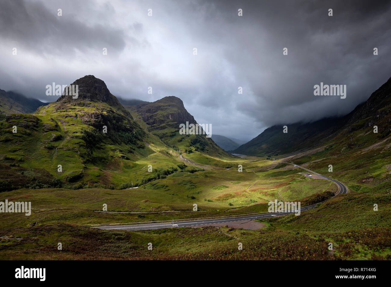 Dark clouds over the valley Glen Coe, road through mountainous countryside, Highlands, Scotland, Great Britain Stock Photo