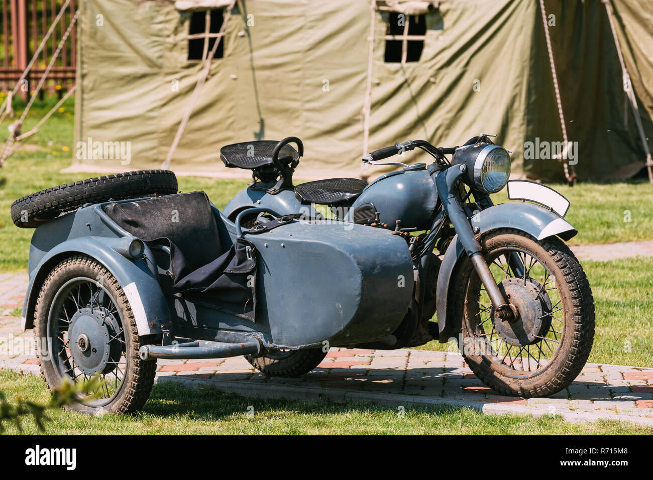 The Old Rarity Tricar, Three-Wheeled Gray Motorcycle With A Sidecar Of German Forces Of World War 2 Time Standing As An Exhibit In Summer Sunny Park. Stock Photo