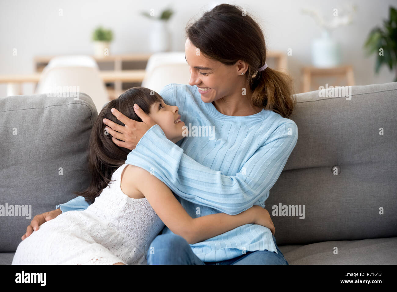 Mulatto mommy and daughter looking at each other sitting indoors Stock Photo