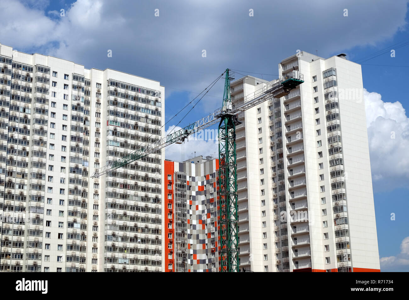 New high-rise modern apartment buildings construction in process ob bright sunny day front view horizontal with focus on construction tower crane Stock Photo