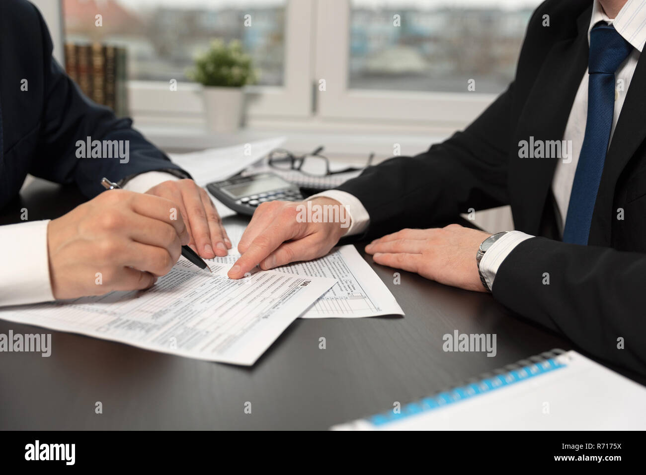 Tax advisor helps to complete US 1040 tax form. Businessmen working in a tax office Stock Photo