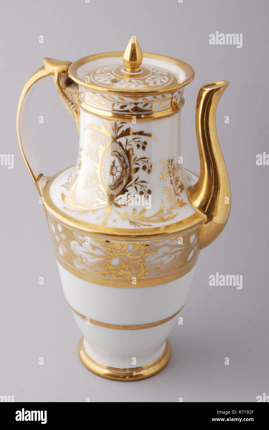 White coffee pot with goldcolored edges and flower, acorn and leaf