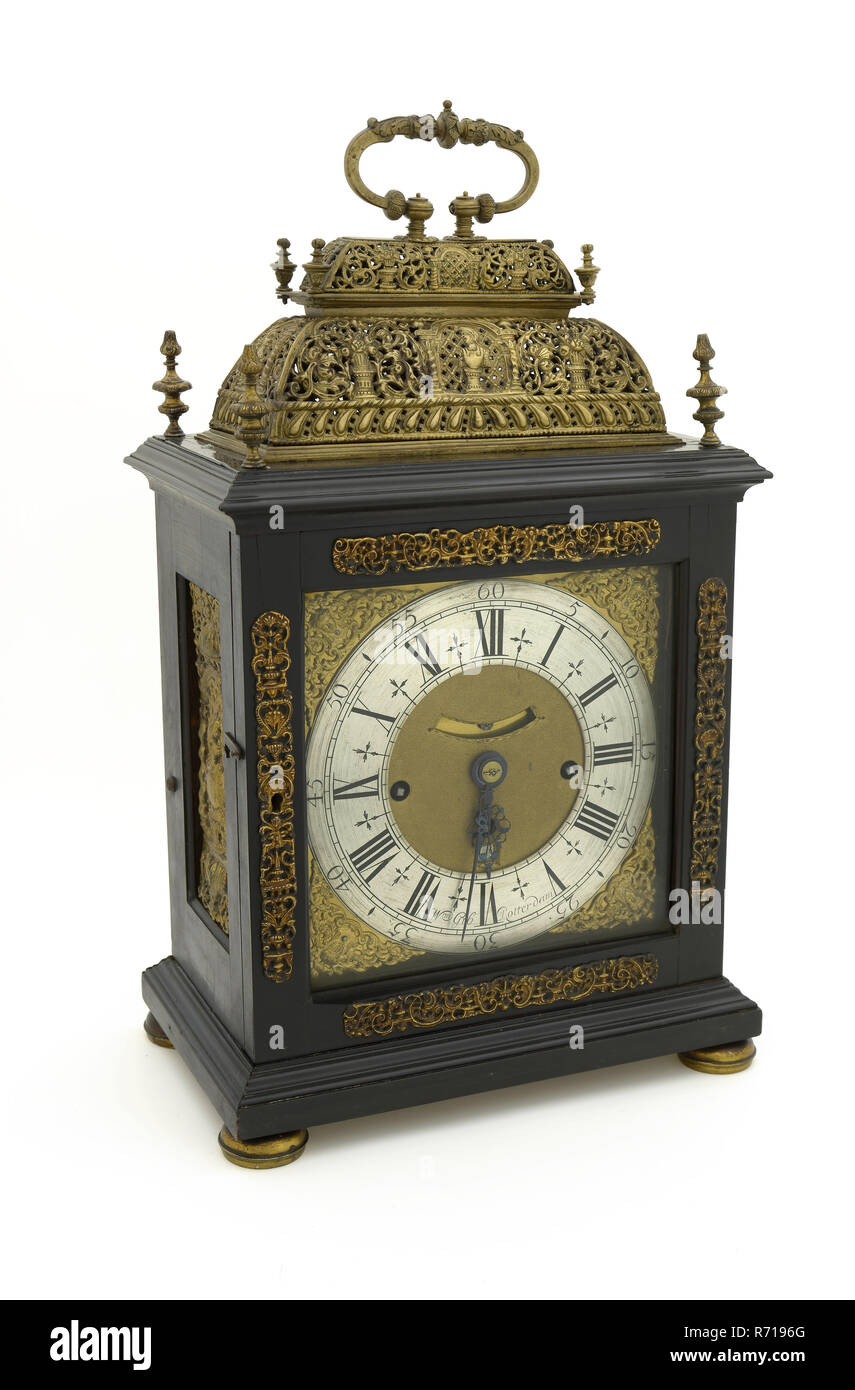 William Gib, Black table-topper with double-basket and in richly engraved backplate, clock clock timepiece measuring instrument wood oak brass steel textile, Rectangular base on four gilded brass reversed bowl-shaped feet with edge in the middle. At the bottom profiled frame around. On the front and rear square door with square glass pane. On the wood of the doors around the glass four driven gilt brass ornaments with rocaille vases and other symmetrical motifs. Along the top surface double profiled frame with four pinnacles on the corner points in the form of an urn with flame. Centrally on t Stock Photo