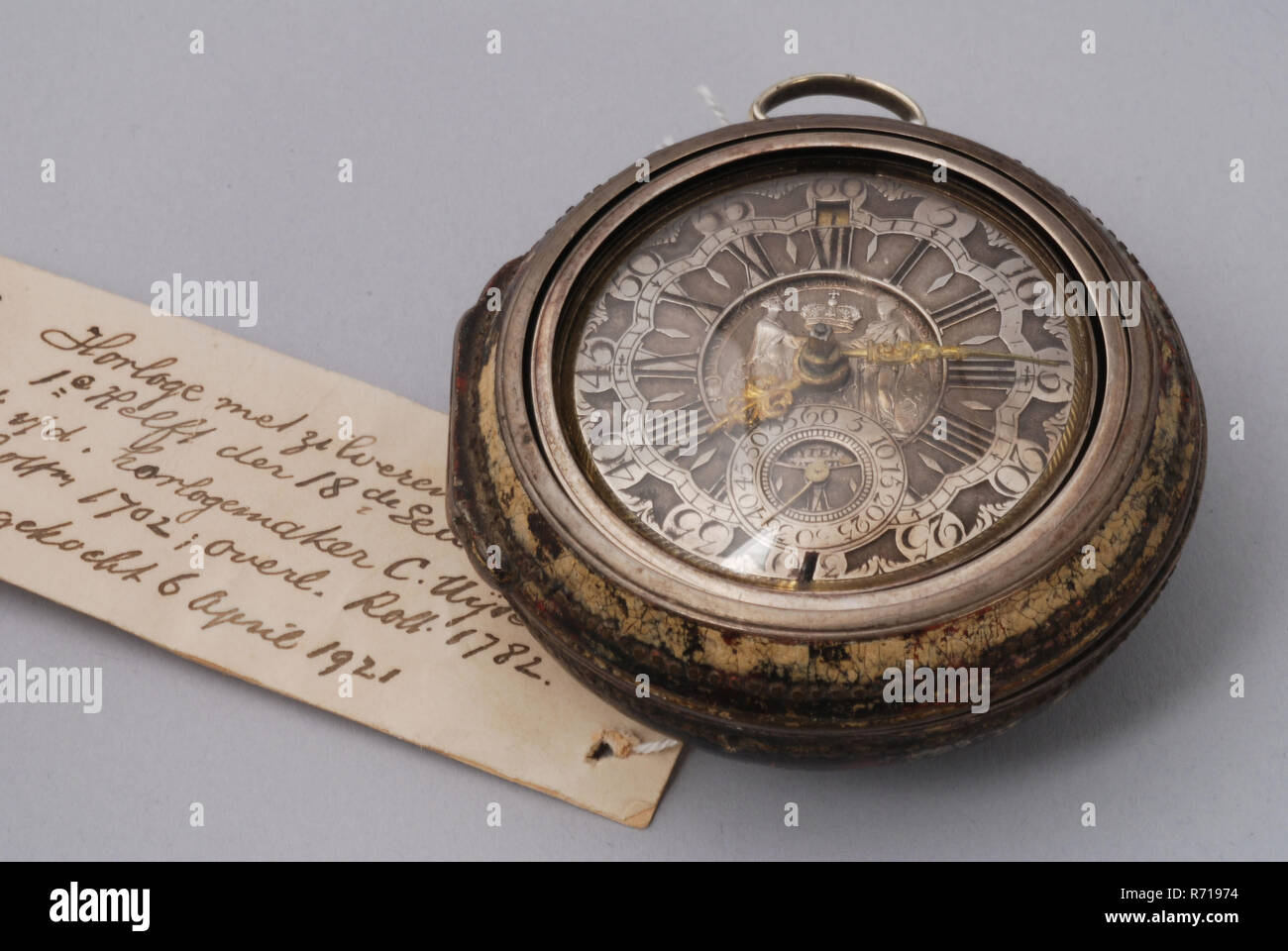 Cornelis Uyterweer, Pocket watch with protective case with imitation tortoise painting and silver dial with date calendar and golden hands, pocket watch watch movement instrument silver brass steel glass textile copper gold exterior cupboard, Dial: silver champlevé with Roman numerals for the hours and Arabic numerals for the minutes. Minute band with so-called 'Dutch' bows. Declaration of seconds on separate ring under the pointer with arabic numbers. signature in recess thereof. In the center of the dial the image of royal couple Deepens hands with crown above it. On the outside of this the  Stock Photo