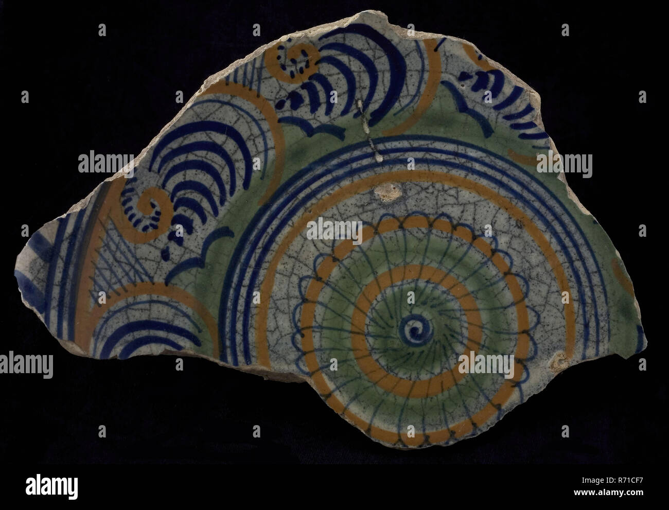 Fragment majolica dish, polychrome, in concentric circles rosette, cable edge, plate crockery holder soil find ceramic earthenware glaze, baked underside covered with lead glaze gray mottled by staying in the bottom and with some black splashes Polychrome archeology Rotterdam City Triangle Providing food inside Serving archaeological find in the soil Binnenvest Rotterdam 1966. Stock Photo