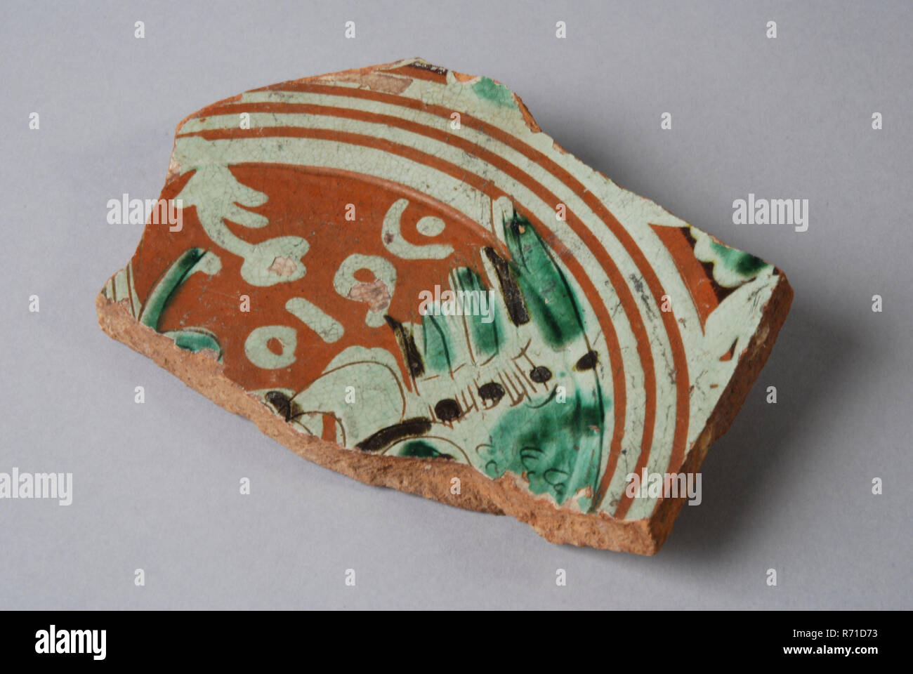 Bottom fragment Werra plate, mirror decor angel, Wing with underneath 1610, pale yellow, brown and green glaze, plate crockery holder soil find ceramic earthenware glaze, Red earthenware with drawing in light yellow and green glaze. date 1610 archeology Stock Photo