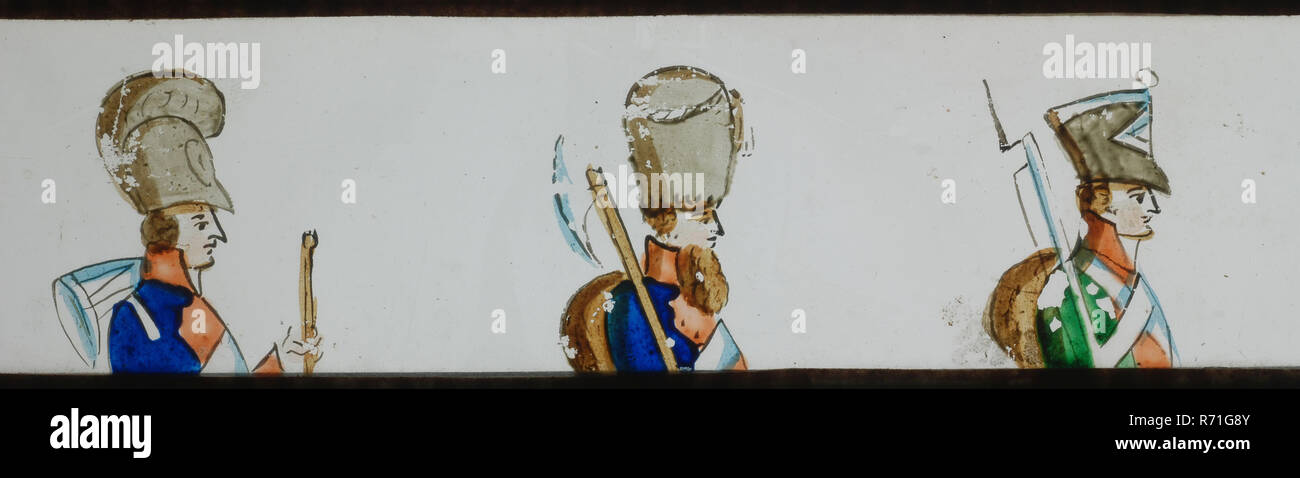 Hand-painted lantern plate with three soldiers, slide slide diapositive footage glass paper, Hand-painted slide with top and bottom edges of white-red checkered paper. Image of three soldiers in early nineteenth century uniforms optics magic lantern magic lantern toy project militaria Stock Photo