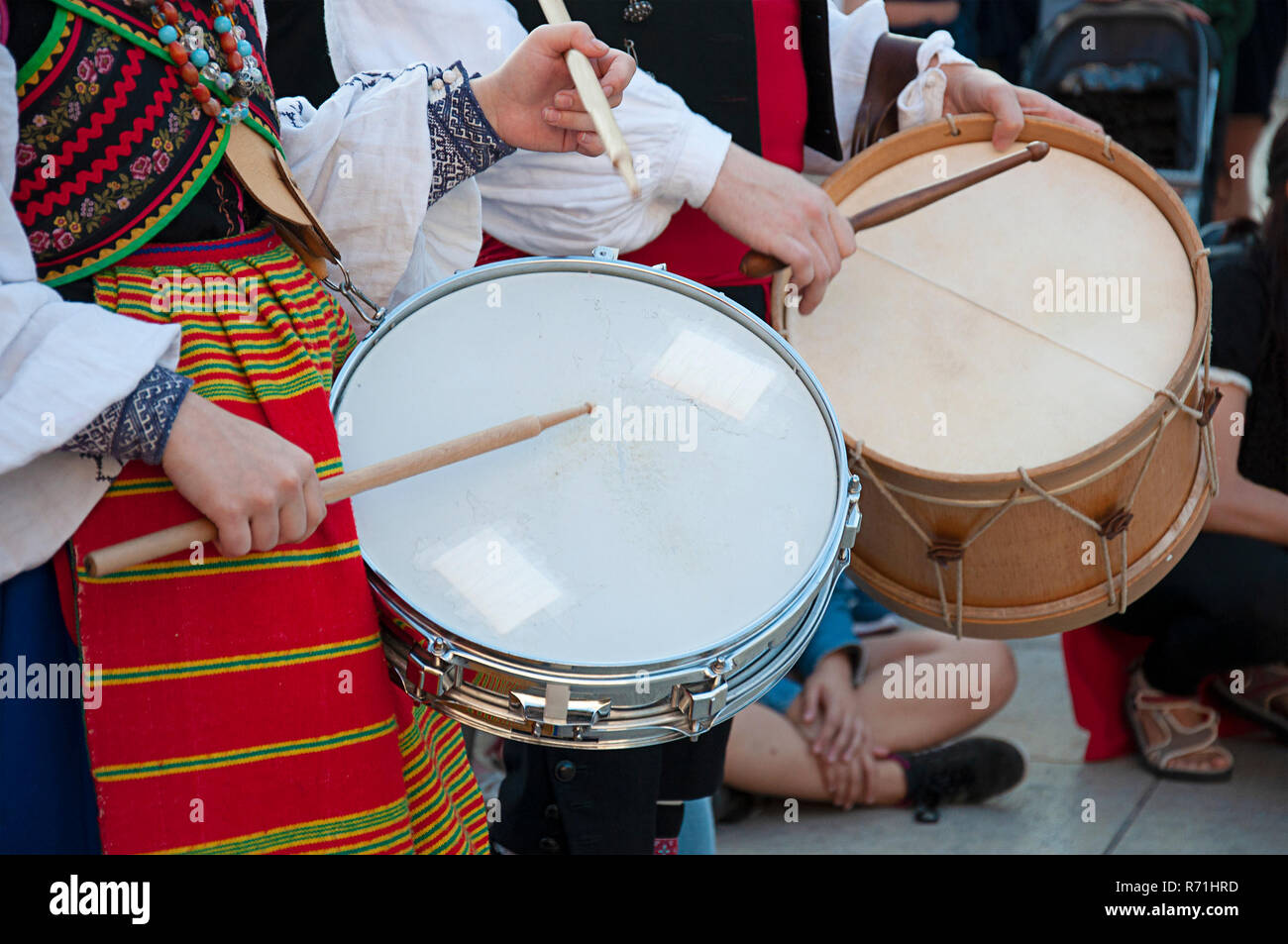 Man and woman playing the drum and wearing one of the traditional