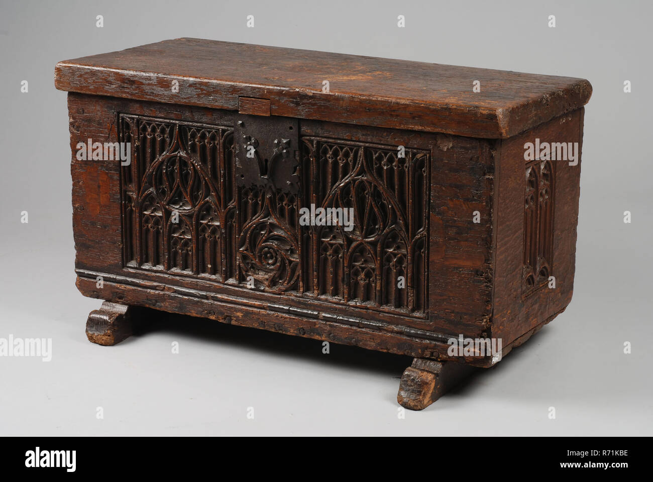 Oak box, casket cabinet furniture furniture interior design wood oak wood paint, Oak box, on two sled legs with carvings in Gothic flamboyant style (with pointed arches and cross flowers) on sides and front. Exterior lock on the outside with decoration on the outside: probably an iron claw lock with single claw. On the back hinges for the lid. On the inside there are crocheted grooves in every corner: did an interior work here before? Rectangular wooden lid, is no longer attached to the box: the remains of hinges are missing as well as the lock fitting (probably hook or harpoon which belong to Stock Photo