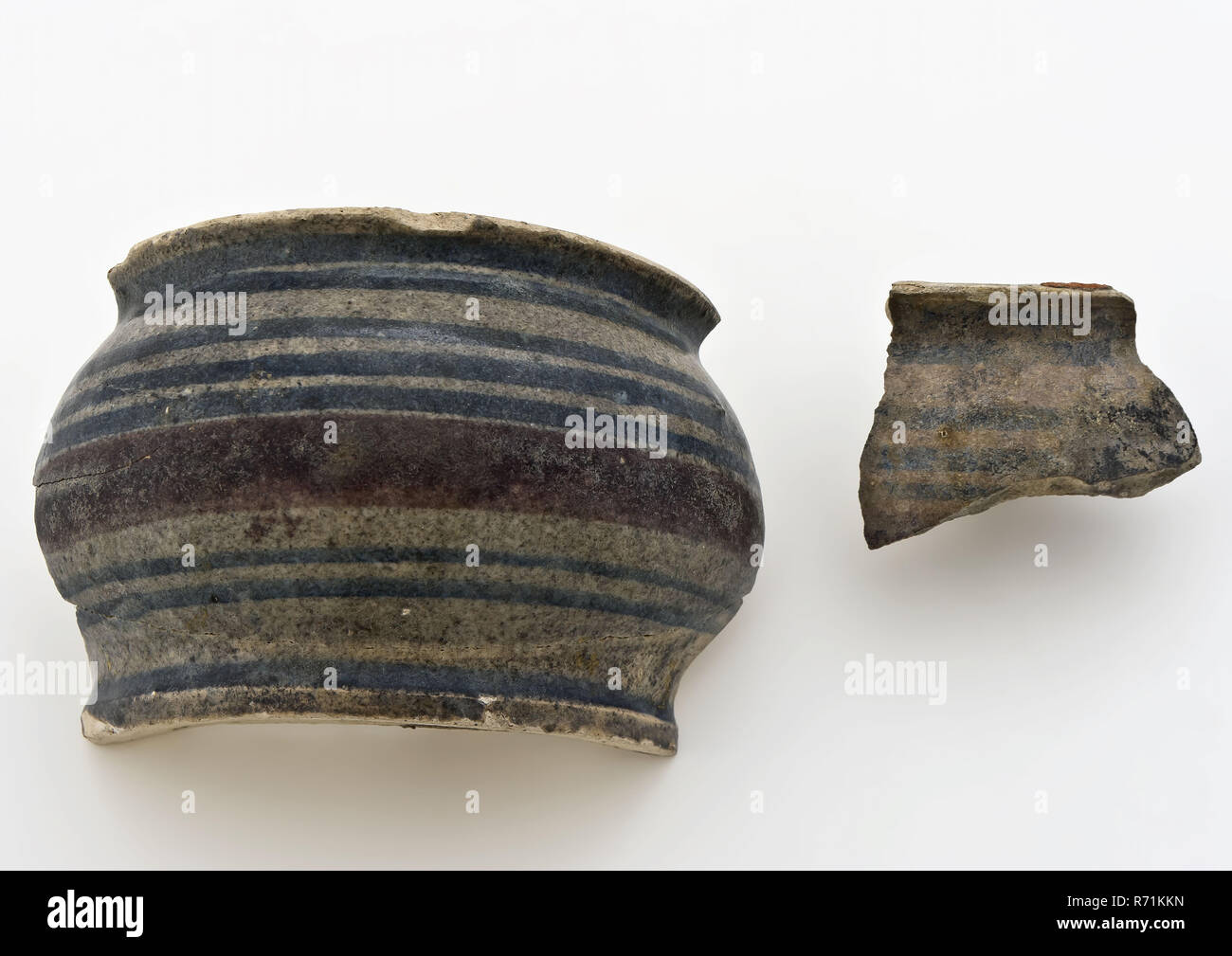 Fragments of majolica ointment jar with polychrome decor, low stomach model, ointment jar apothecary jar holder fragment soil find ceramic earthenware glaze tin glaze lead glaze, hand turned baked glazed decorated baked Fragment of ointment jar with polychrome decor. Blue piping and wide manganese purple band across the belly. Low and wide model with belly. Stand with traces of traces Slightly protruding upper edge Internally covered with green lead glaze Dark discolored by staying in the bottom (). Small edge fragment, archeology Rotterdam IJsselmonde health care indigenous pottery ointment c Stock Photo