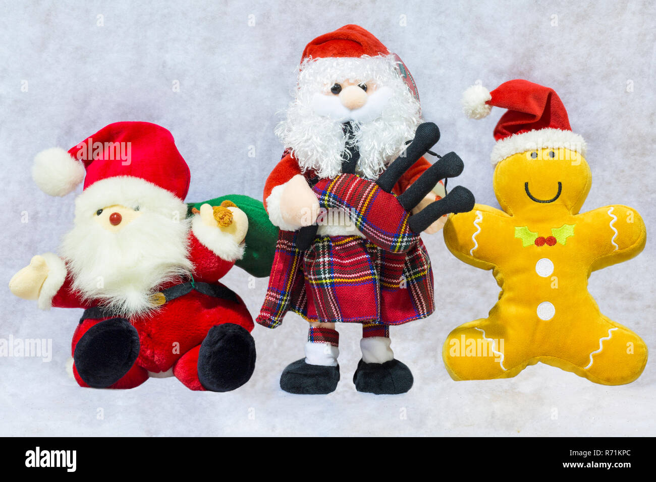 Christmas soft toys - Father Christmas playing bagpipes, Santa Claus with sack and Santa Gingerbread man Stock Photo
