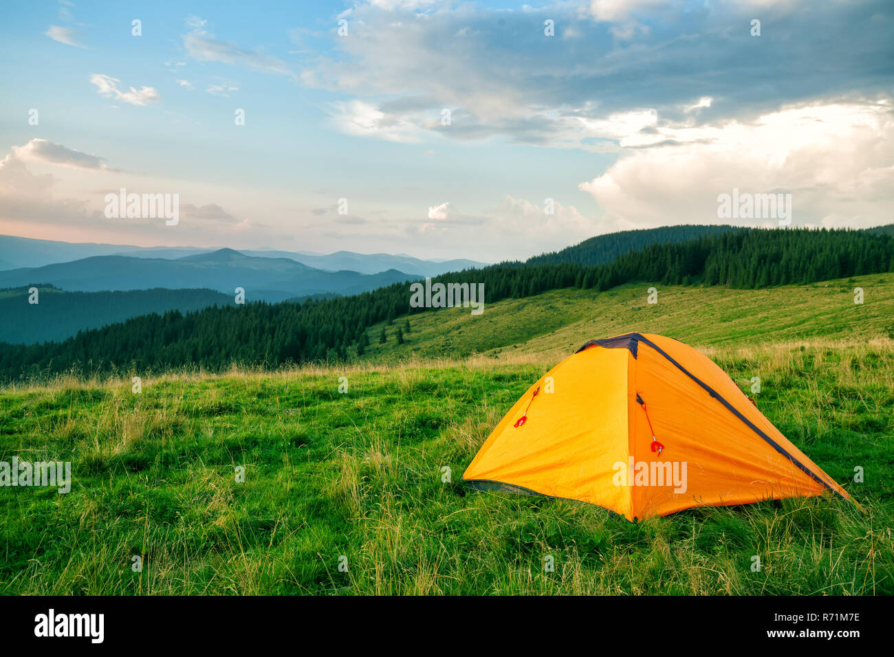 Orange tourist tent in the green mountains Stock Photo