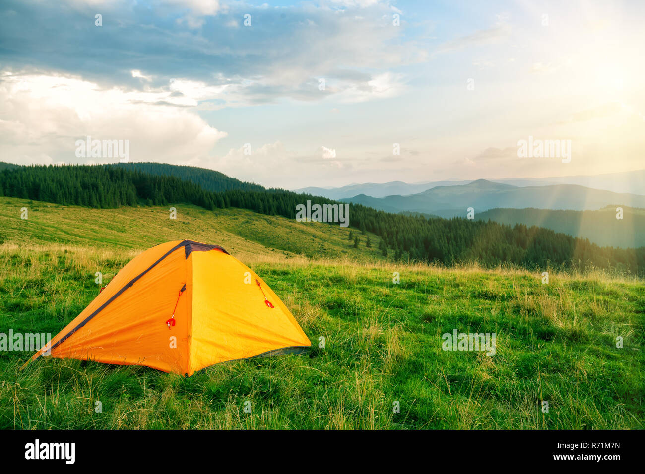 Orange tourist tent in the mountains under the bright sun Stock Photo